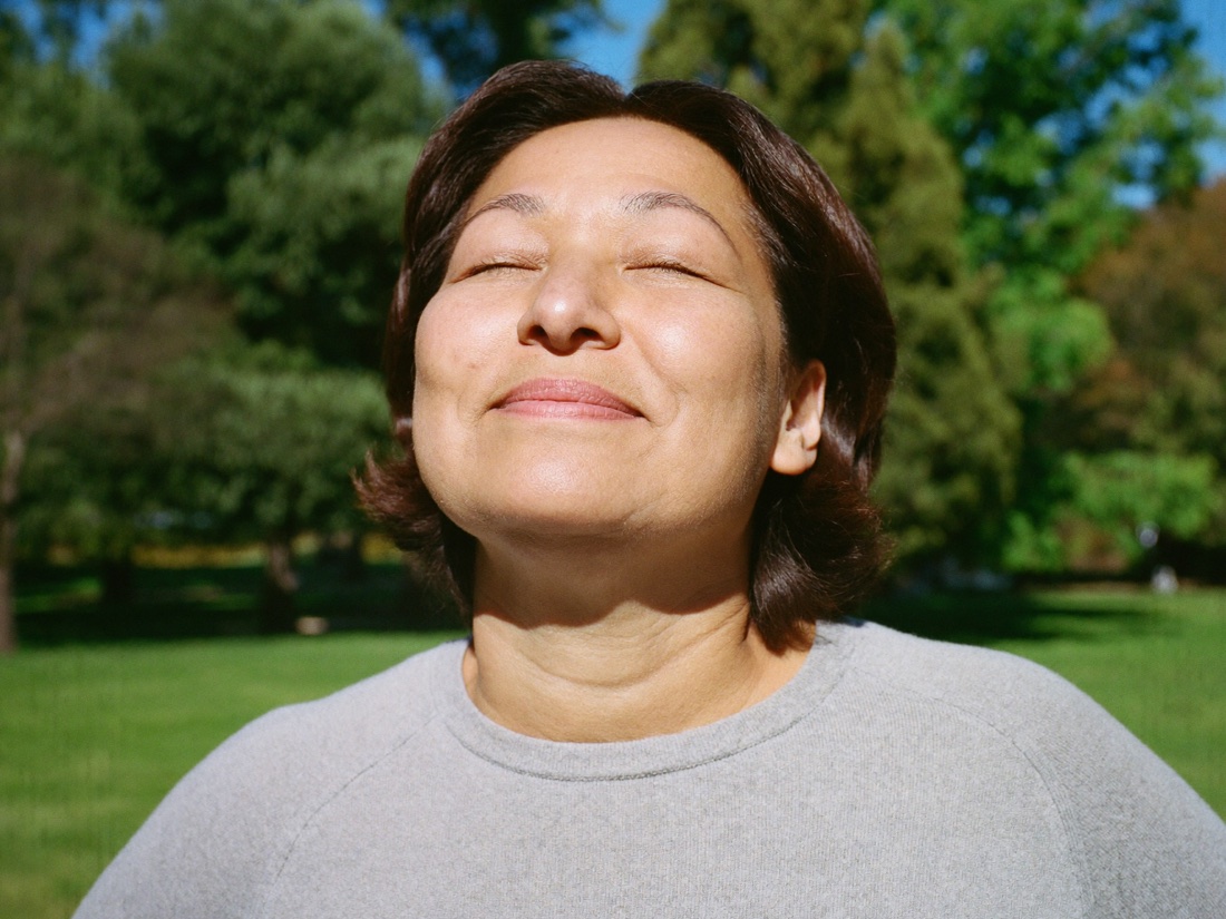 A woman taking a deep breath outdoors